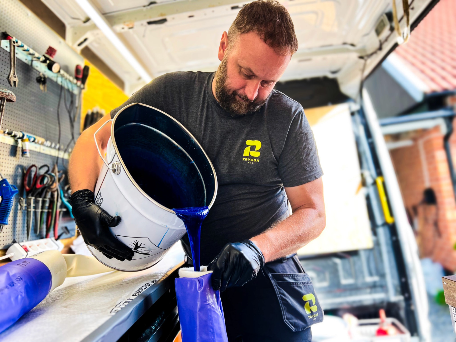 Tekniker från Trygga Rör häller blå epoxi i en relinerstrumpa i servicebilen